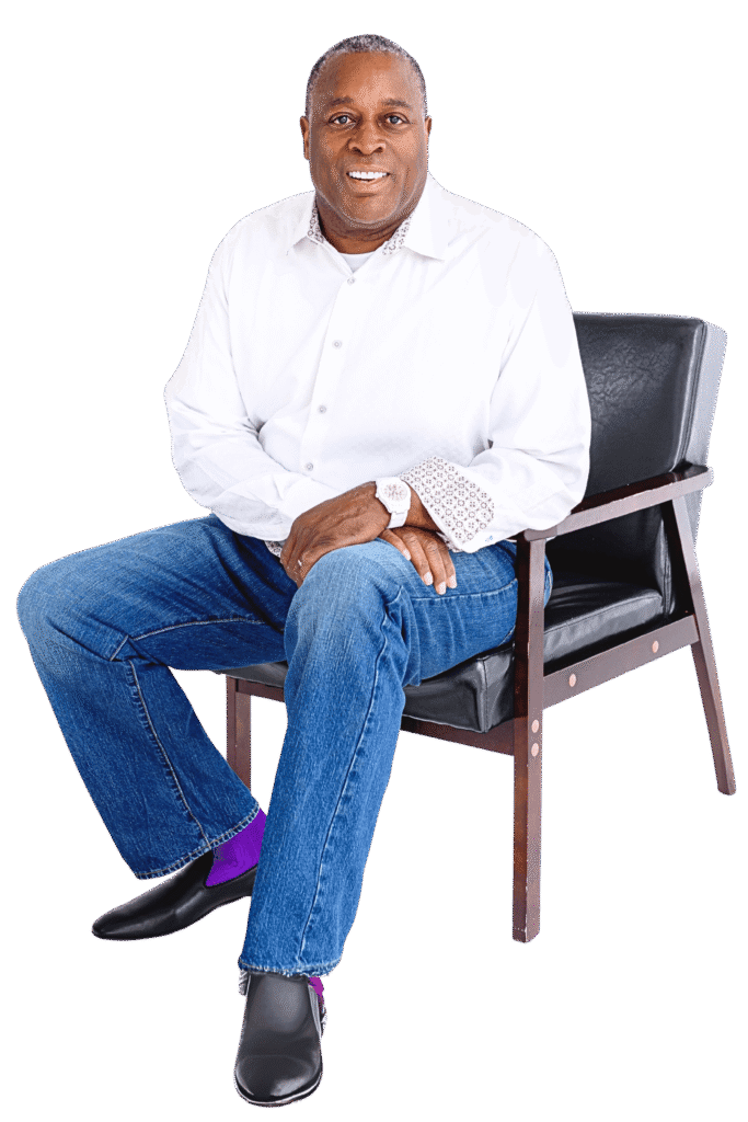 Joel L. Smith, a professionally dressed man in a white shirt and jeans, seated and smiling confidently.